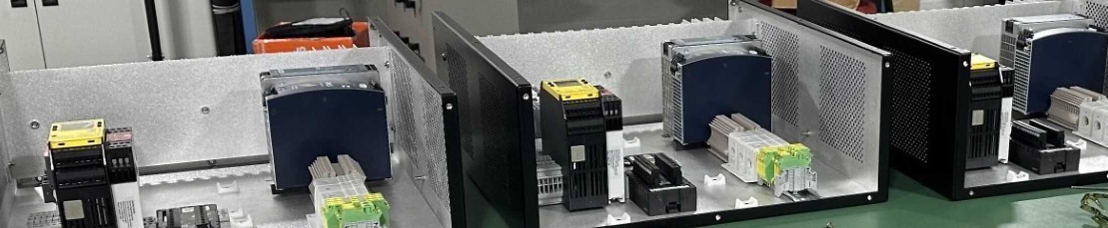 Row of open electro mechanical enclosures on the HPN Electronics production floor, showing internal wiring and components